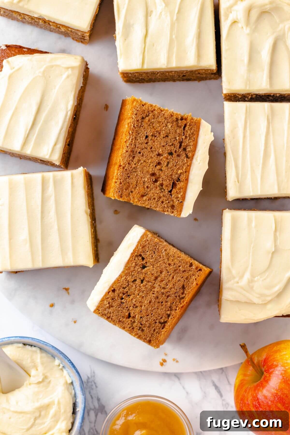 slices of applesauce cake with cream cheese icing placed on marble surface.