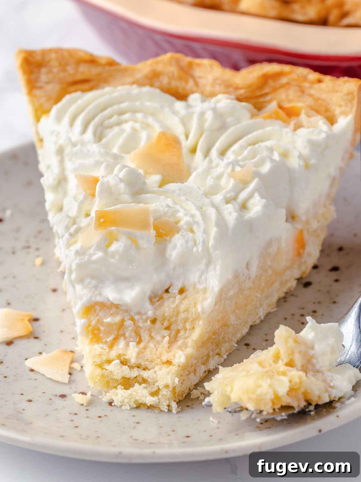 Luscious Coconut Cream Pie 2 A delectable slice of homemade coconut cream pie with a bite taken out, showcasing the creamy filling, crisp crust, and fluffy whipped cream, inviting indulgence.