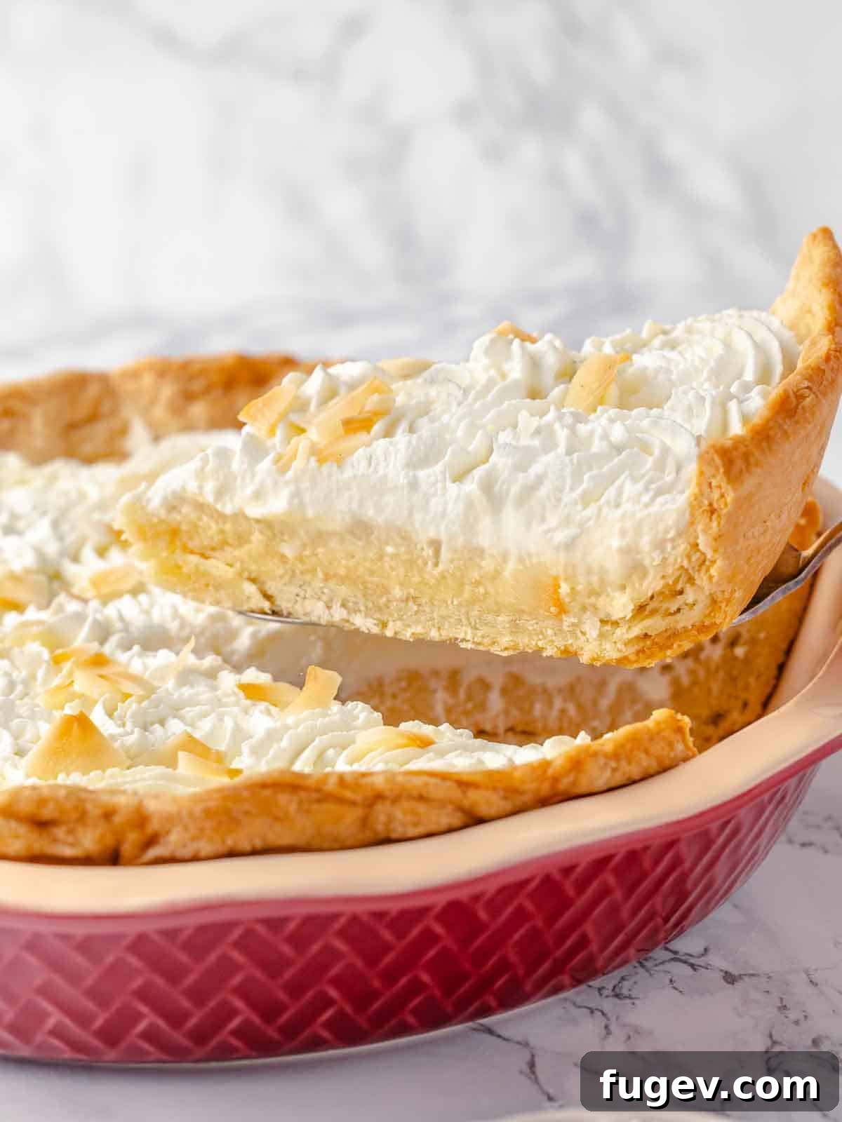 Luscious Coconut Cream Pie 14 A perfectly portioned slice of homemade coconut cream pie, served from a vibrant red pie dish, ready to be enjoyed as a delightful dessert.