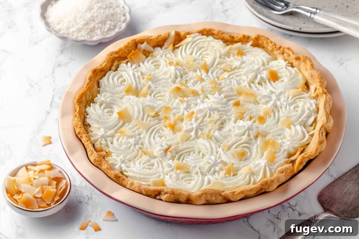 Luscious Coconut Cream Pie 3 A beautiful whole coconut cream pie topped with elegant swirls of homemade whipped cream and a generous sprinkle of toasted coconut, showcasing its festive appeal.