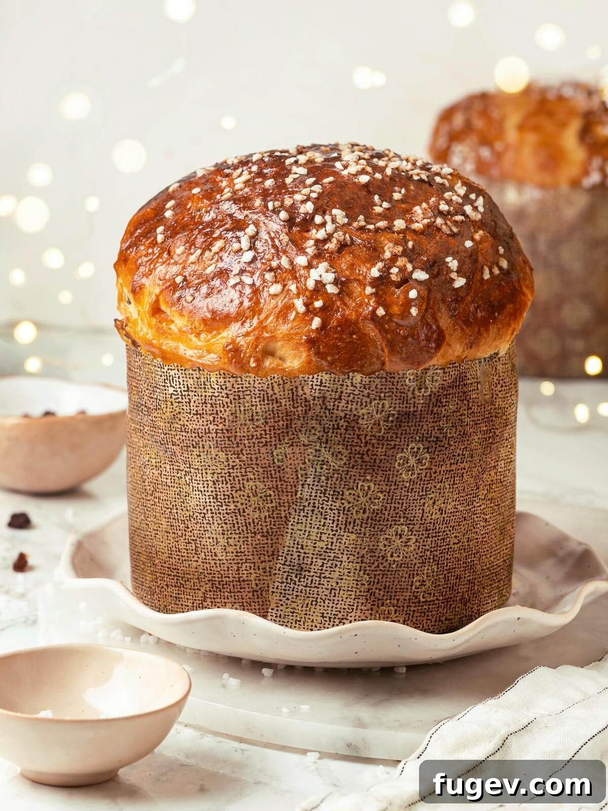 Traditional Italian Panettone 2 The outside of a golden-brown panettone loaf, elegantly decorated with studded sugar and baked in a traditional paper mold, promising a delightful holiday treat.