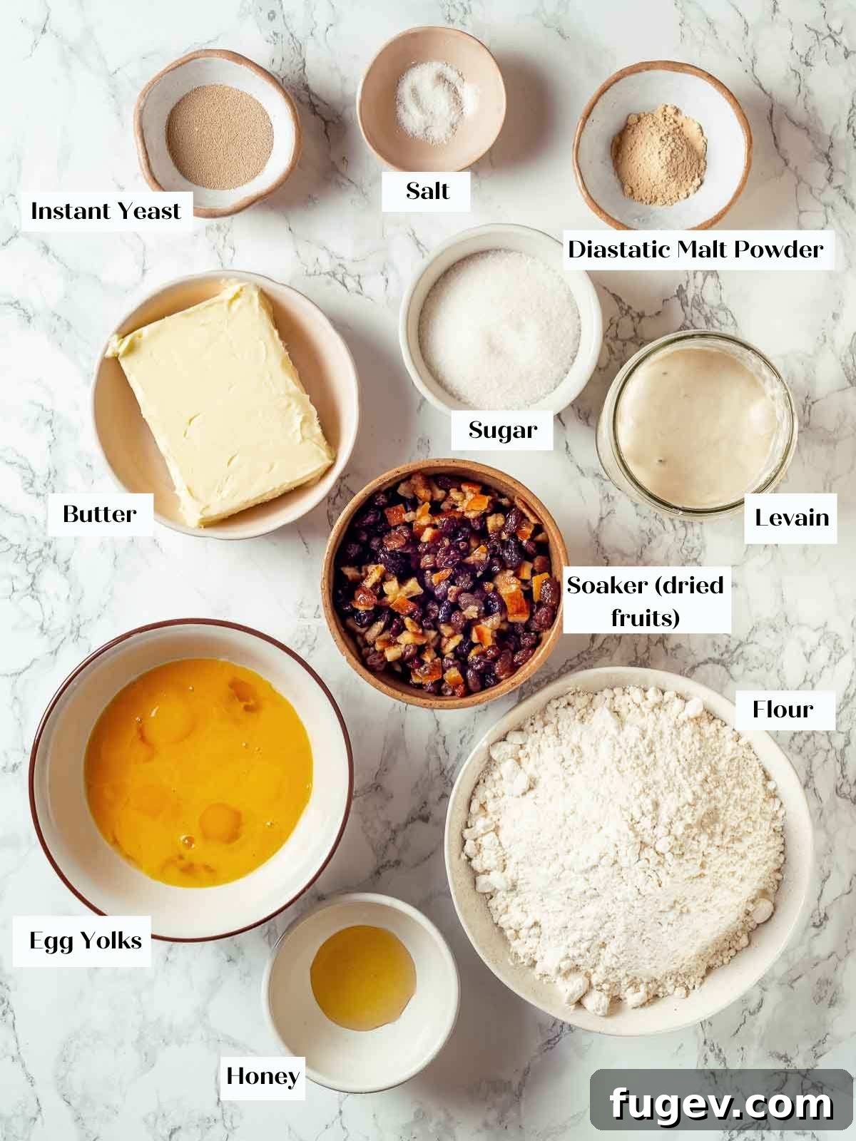 Traditional Italian Panettone 4 Neatly arranged ingredients for panettone, including dried fruits, citrus peels, flour, and eggs, on a pristine white marble countertop.