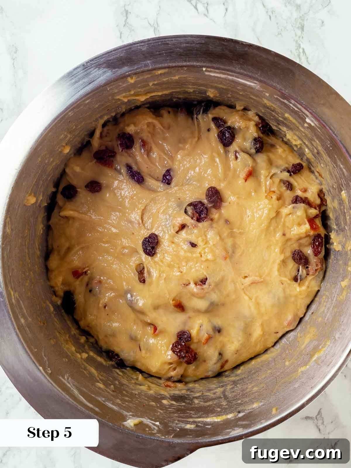 Traditional Italian Panettone 9 The vibrant fruit soaker being gently added to the panettone dough during the final stages of mixing, ensuring even distribution.