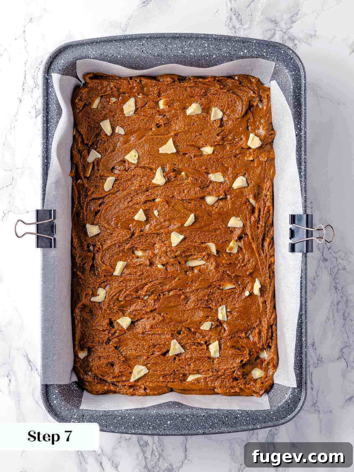 Chewy Gingerbread Blondies 11 Unbaked gingerbread blondie batter smoothly spread into a rectangular baking pan, neatly lined with parchment paper, and ready to be placed in the oven.
