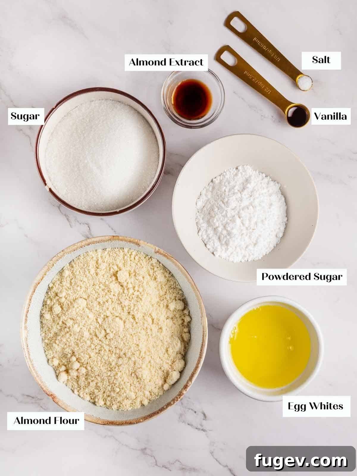 Italian Almond Amaretti 4 A flat lay of the essential amaretti cookie ingredients: almond flour, granulated sugar, powdered sugar, egg whites, vanilla extract, and almond extract.