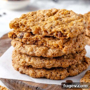 A cowboy cookie broken in half, revealing its dense, chewy interior packed with a delightful mix of oats, chocolate chips, pecans, and coconut flakes.