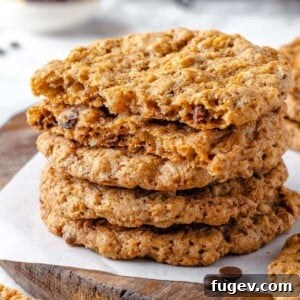 A cowboy cookie broken in half, showing a dense and chewy interior filled with mix-ins.