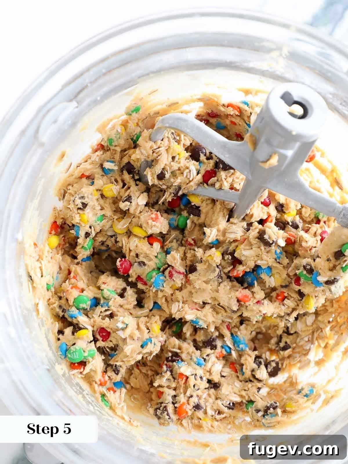 Ultimate Monster Cookies 9 A clear mixing bowl filled with chunky monster cookie dough packed with mix-ins.