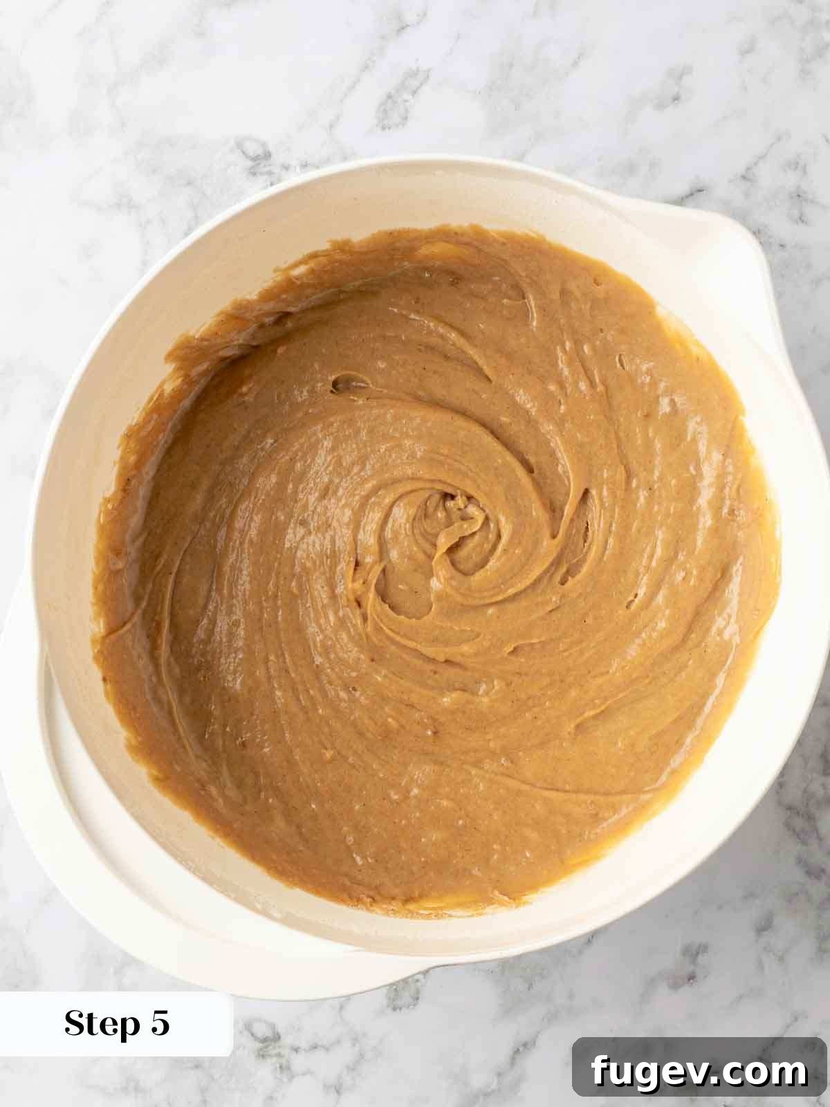 Luscious Banana Cake with Tangy Cream Cheese Frosting 7 A mixing bowl filled with creamy, smoothly combined banana cake batter, perfectly mixed and ready for baking.