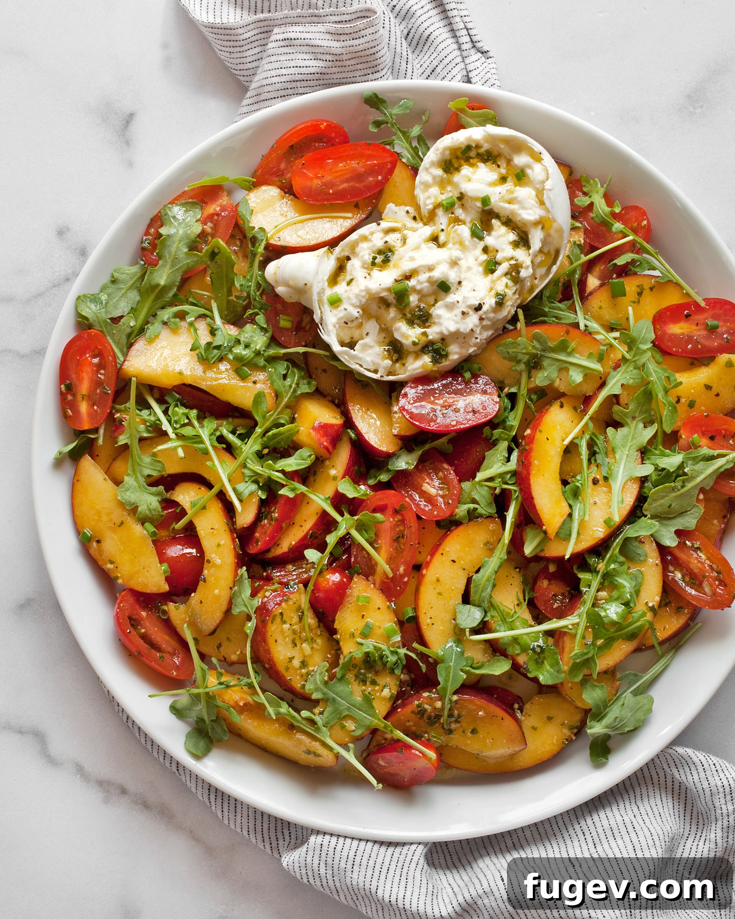 Sun-Kissed Peach, Tomato & Burrata Salad 3 A close-up shot of the fresh tomato peach burrata salad, showcasing its vibrant colors and appealing textures on a ceramic plate.