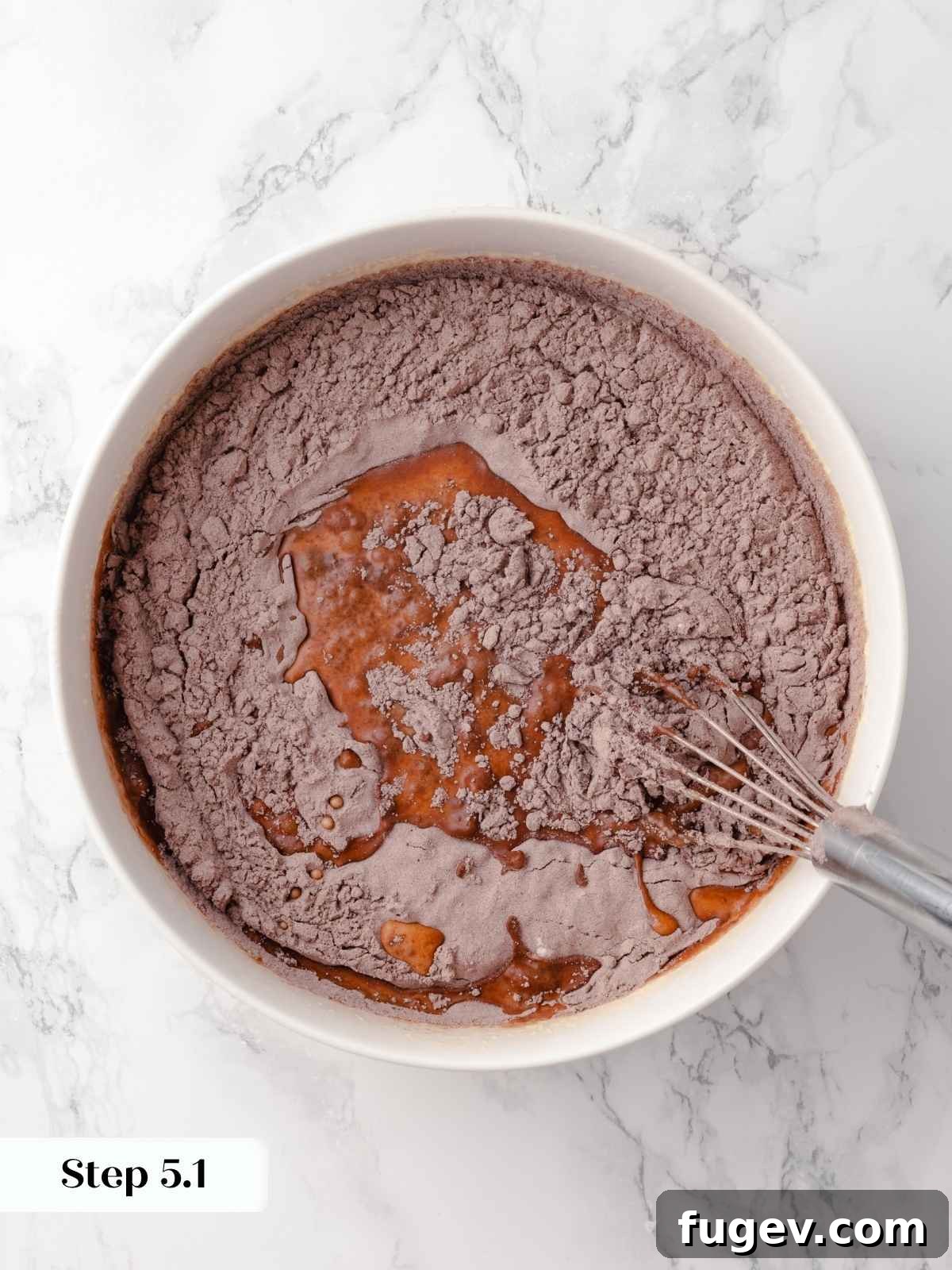 Decadent Chocolate Raspberry Indulgence 11 Dry ingredients being gradually added to wet ingredients in a mixing bowl for the chocolate cake batter.