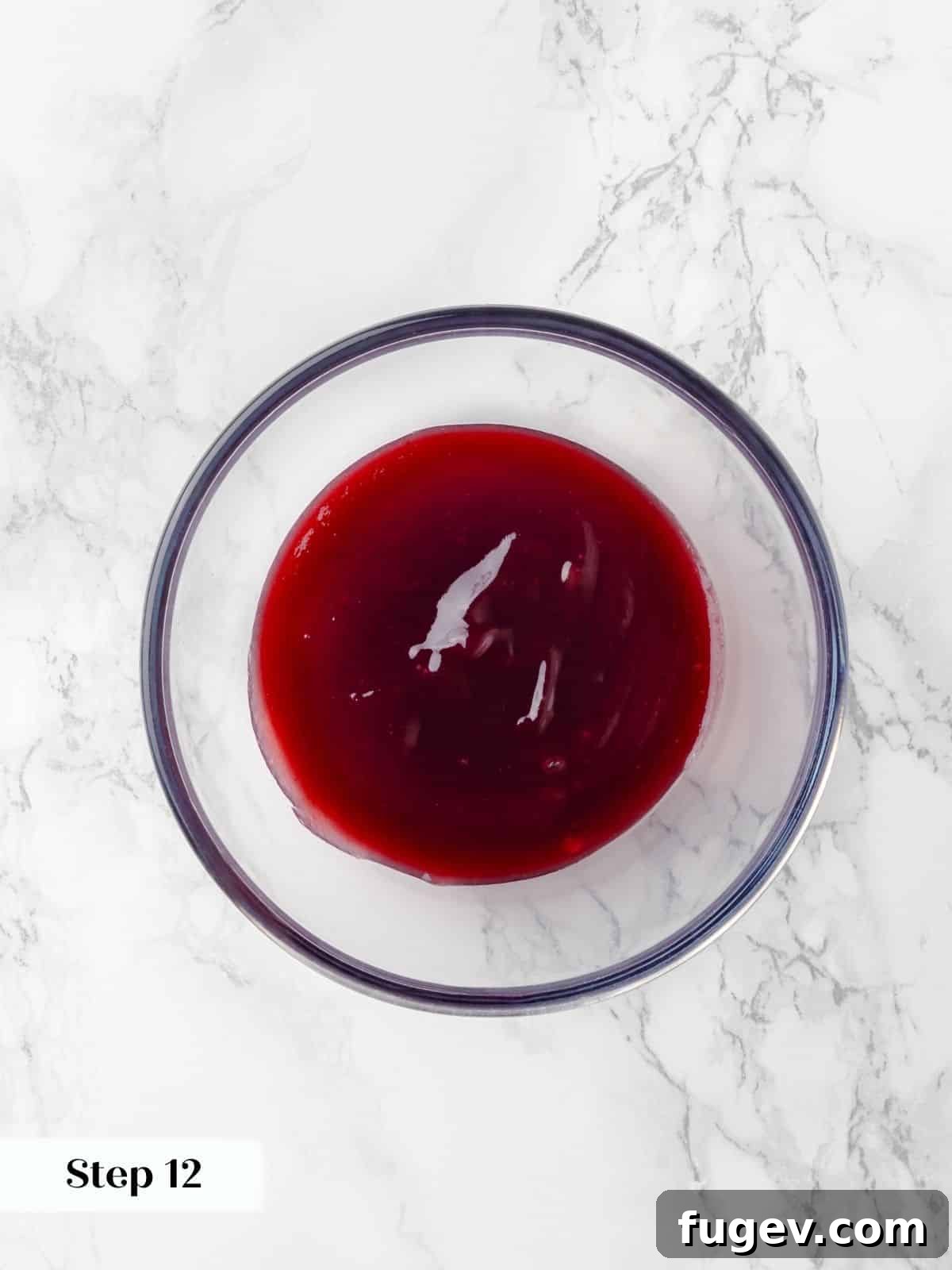 Decadent Chocolate Raspberry Indulgence 16 A clear glass bowl filled with vibrant, smooth raspberry jam, glistening and ready to be chilled for the cake layers.