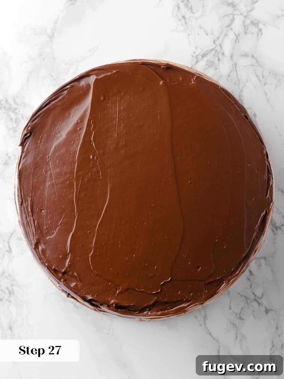 Decadent Chocolate Raspberry Indulgence 27 Rich chocolate fudge frosting being smoothly applied to the top layer of the cake with an offset spatula, creating a polished finish.
