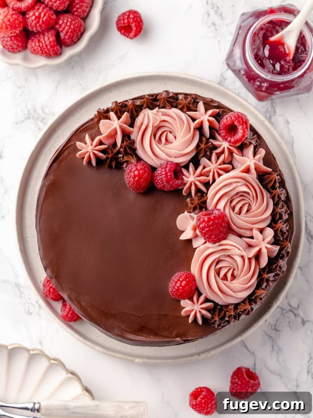 Decadent Chocolate Raspberry Indulgence 28 The fully decorated chocolate raspberry cake, elegantly covered in chocolate fudge frosting and adorned with swirls of pink buttercream and fresh raspberries.