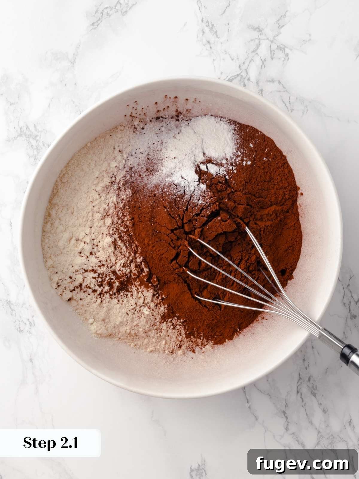 Decadent Chocolate Raspberry Indulgence 5 A bowl of dry ingredients being combined with a whisk for the chocolate cake batter, including flour and cocoa powder.