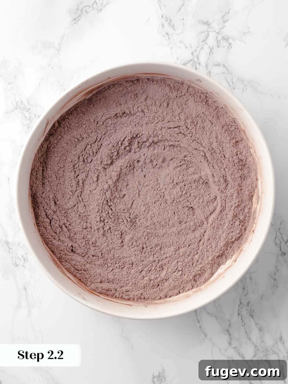 Decadent Chocolate Raspberry Indulgence 6 Dry ingredients for the cake, including cocoa powder and flour, thoroughly mixed together in a bowl, ready for the wet ingredients.