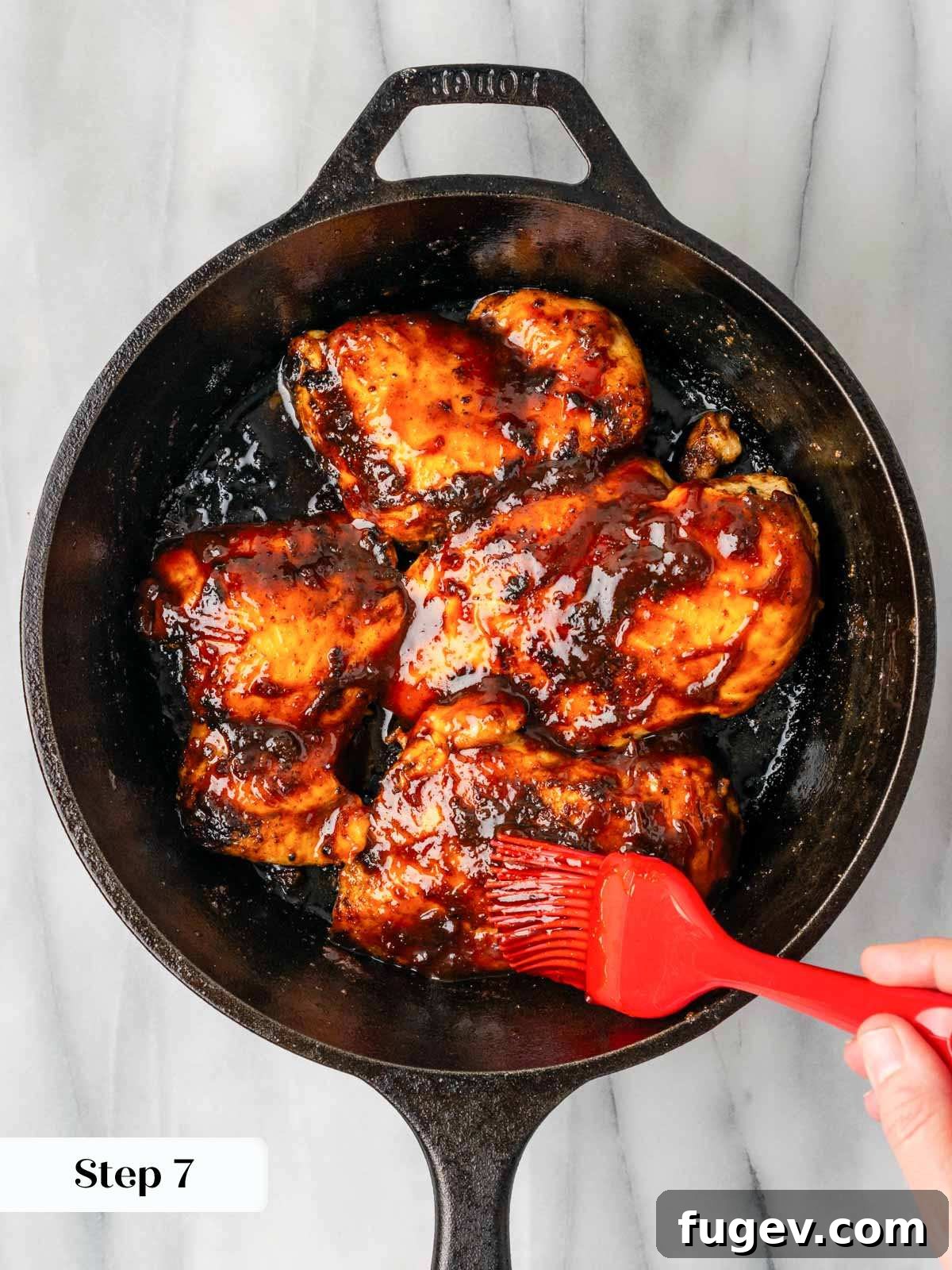 Tender Oven-Baked BBQ Chicken Breast 11 Brushing maple chipotle bbq sauce onto baked chicken breasts in a cast iron skillet during the final baking stage.