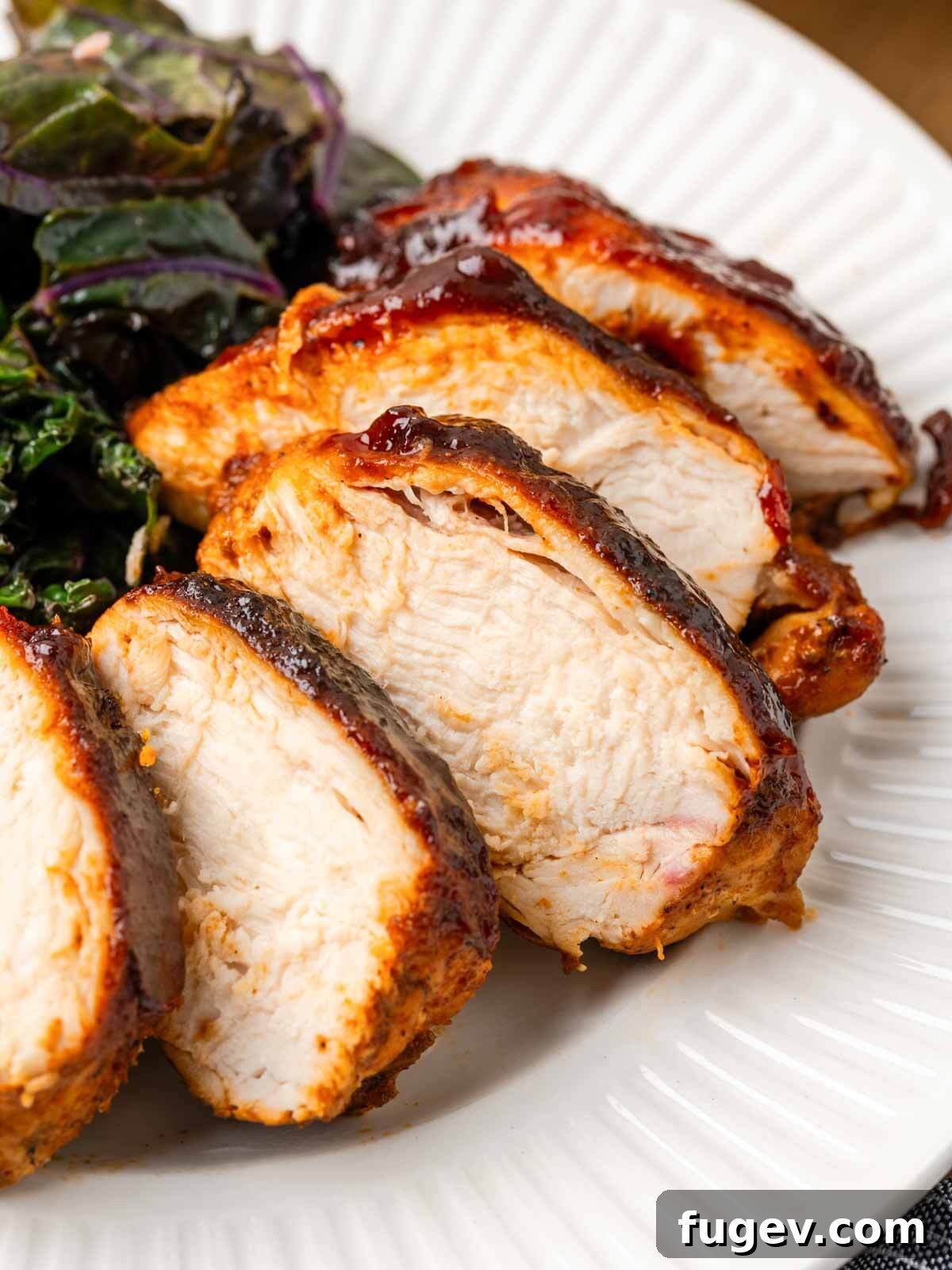Tender Oven-Baked BBQ Chicken Breast 12 Perfectly sliced baked bbq chicken breast on a white plate, showcasing its juicy interior.