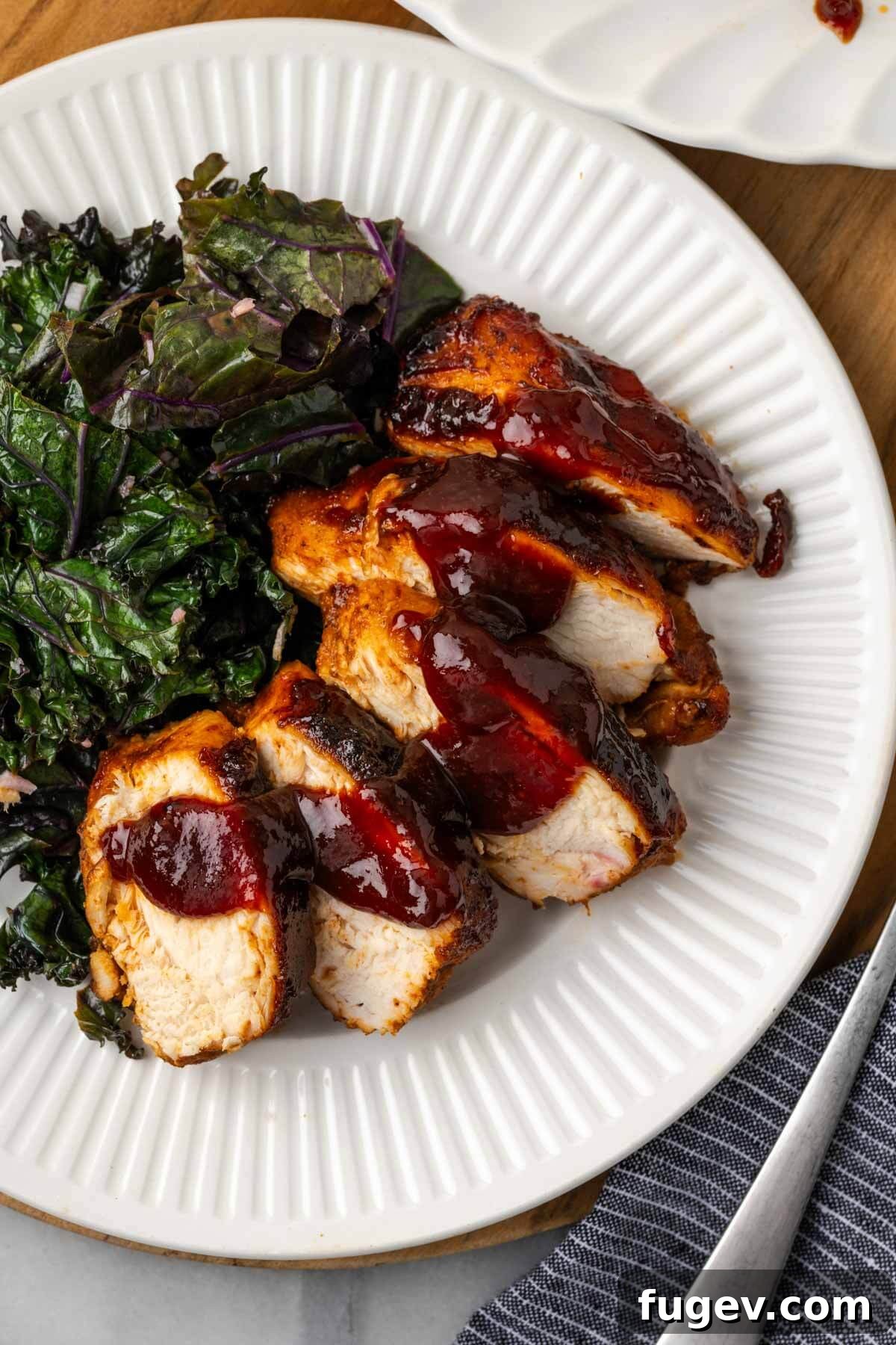 Tender Oven-Baked BBQ Chicken Breast 3 Deliciously sauced and sliced baked bbq chicken on a white plate, ready to serve.