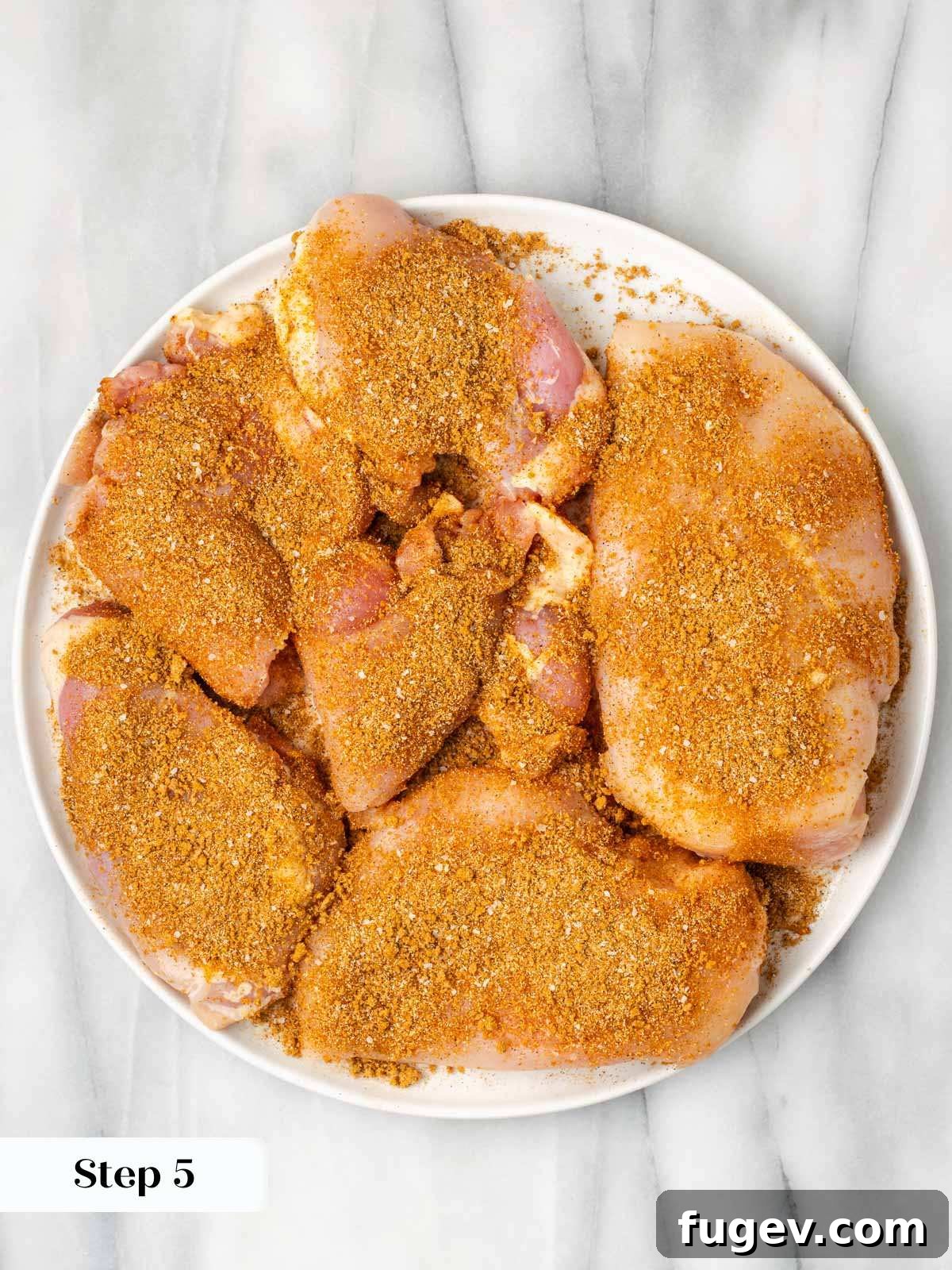 Tender Oven-Baked BBQ Chicken Breast 9 Chicken breasts generously coated with dry rub seasoning on a white plate.