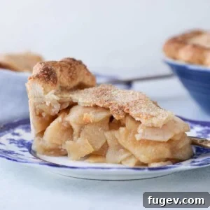 A perfect slice of Mile High Apple Pie on a blue plate, revealing its impressive height and delicious filling.