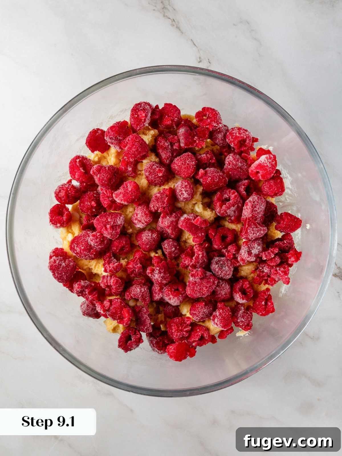 Velvet White Chocolate Raspberry Cookies 12 Vibrant frozen raspberries being gently folded into the cookie dough, adding bursts of tart, fruity flavor without breaking apart.