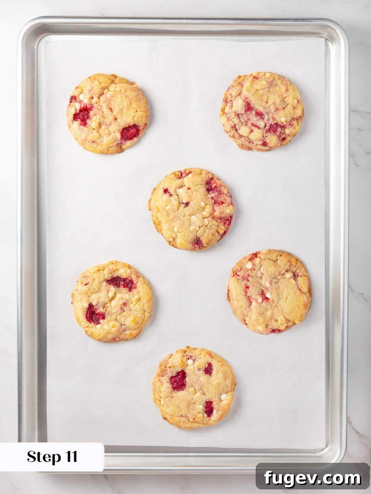 Velvet White Chocolate Raspberry Cookies 15 A baking tray filled with golden-brown, freshly baked white chocolate raspberry cookies, just removed from the oven and beginning to cool.