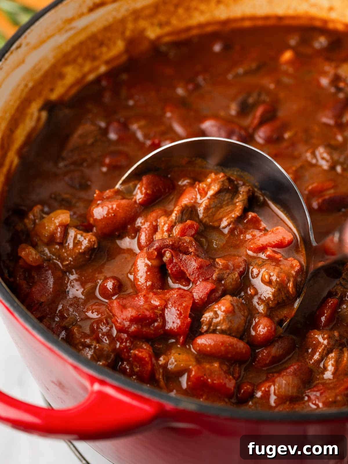 Hearty Steak Chili 2 Serving rosemary pinot noir steak chili with a ladle into a bowl.