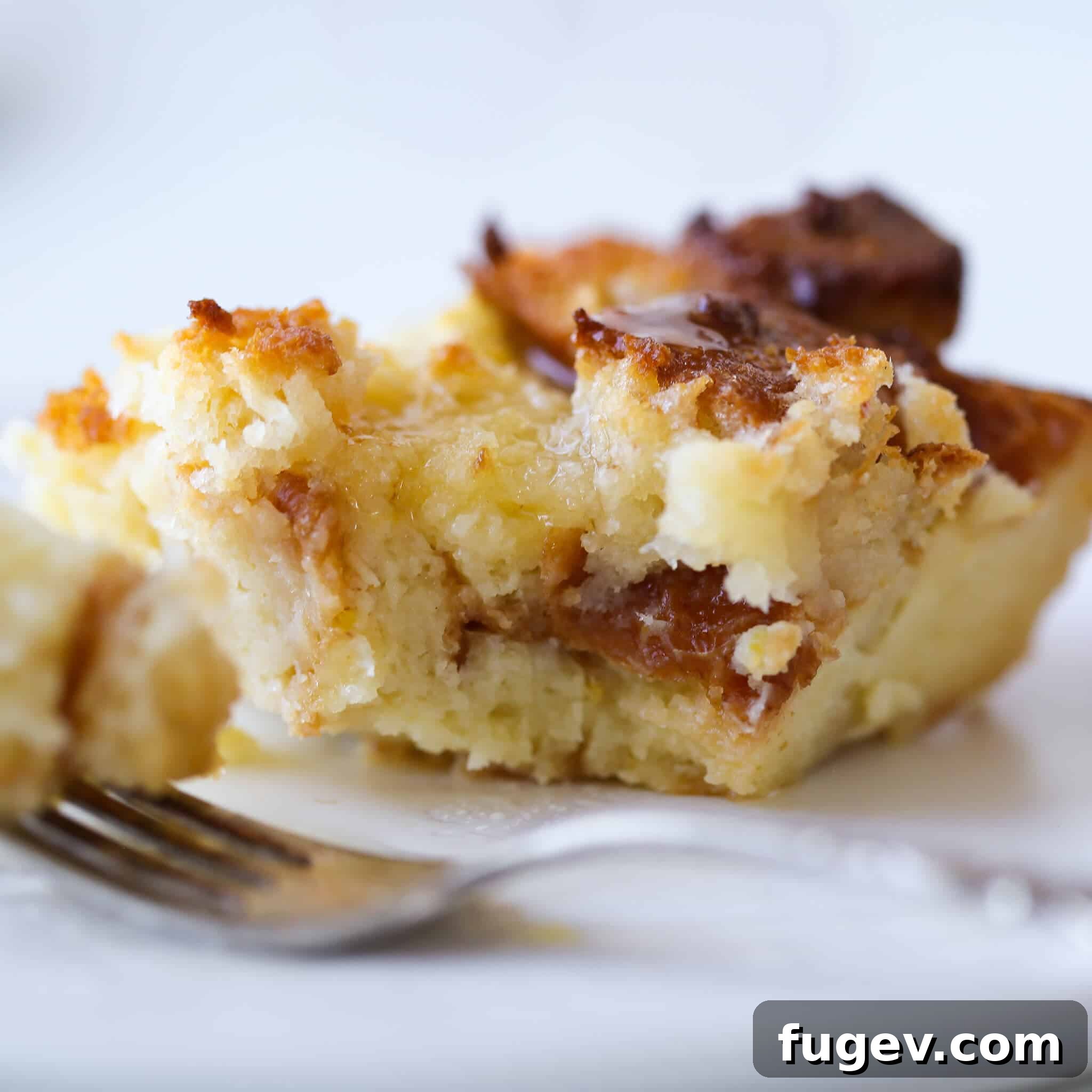 Zesty Lemon Bread Pudding 5 A close-up of a Lemon Raspberry Bread Pudding slice on a white plate, highlighting its moist interior