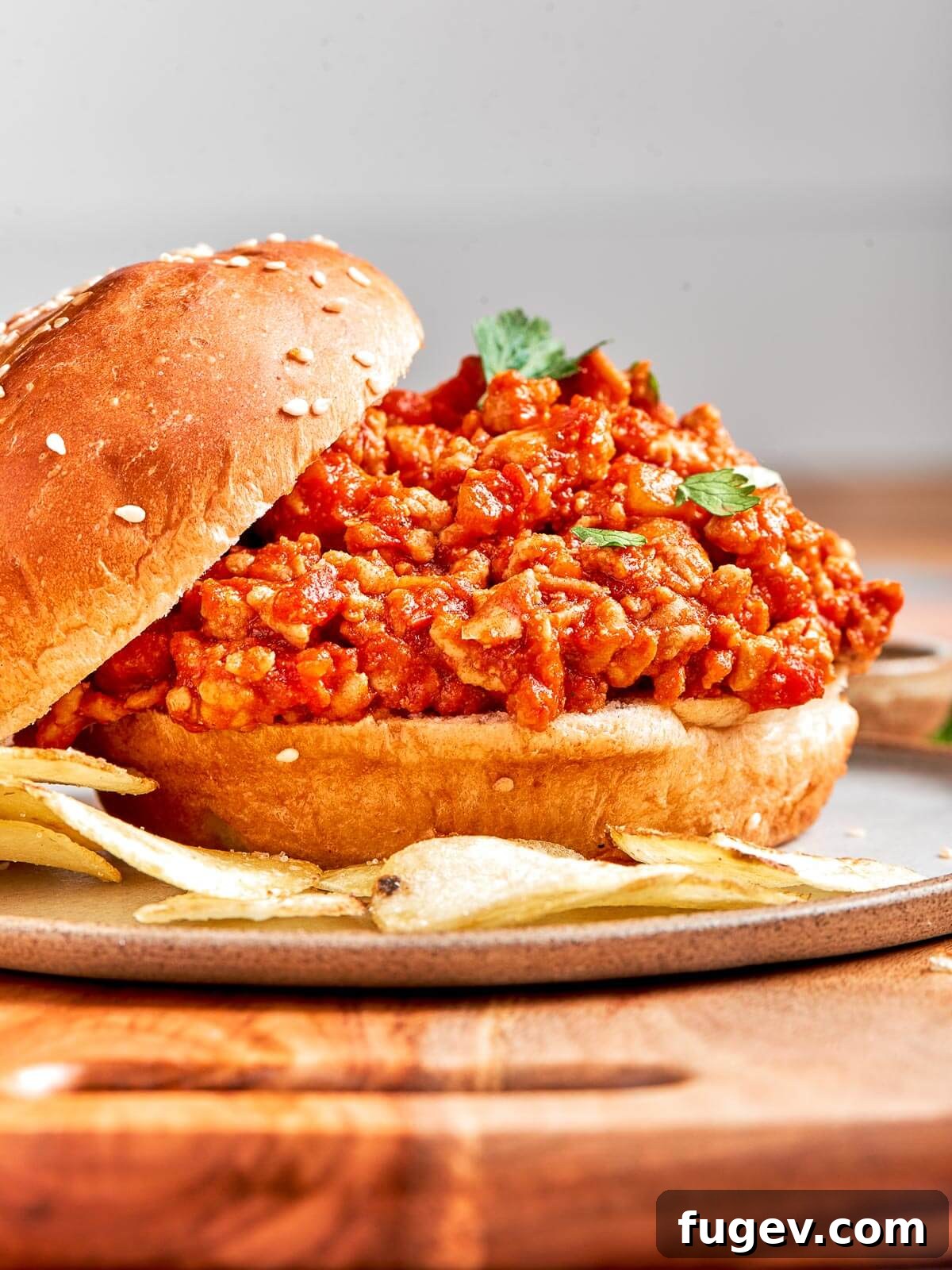 Homestyle Turkey Sloppy Joes 2 A generous serving of healthy turkey sloppy joe filling overflowing from a soft hamburger bun, showcasing its rich, savory texture.