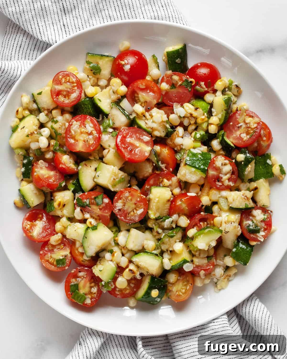 Summer Corn & Zucchini Medley 2 Vibrant grilled zucchini corn salad with cherry tomatoes, scallions, and Parmesan on a white plate, ready to be served.