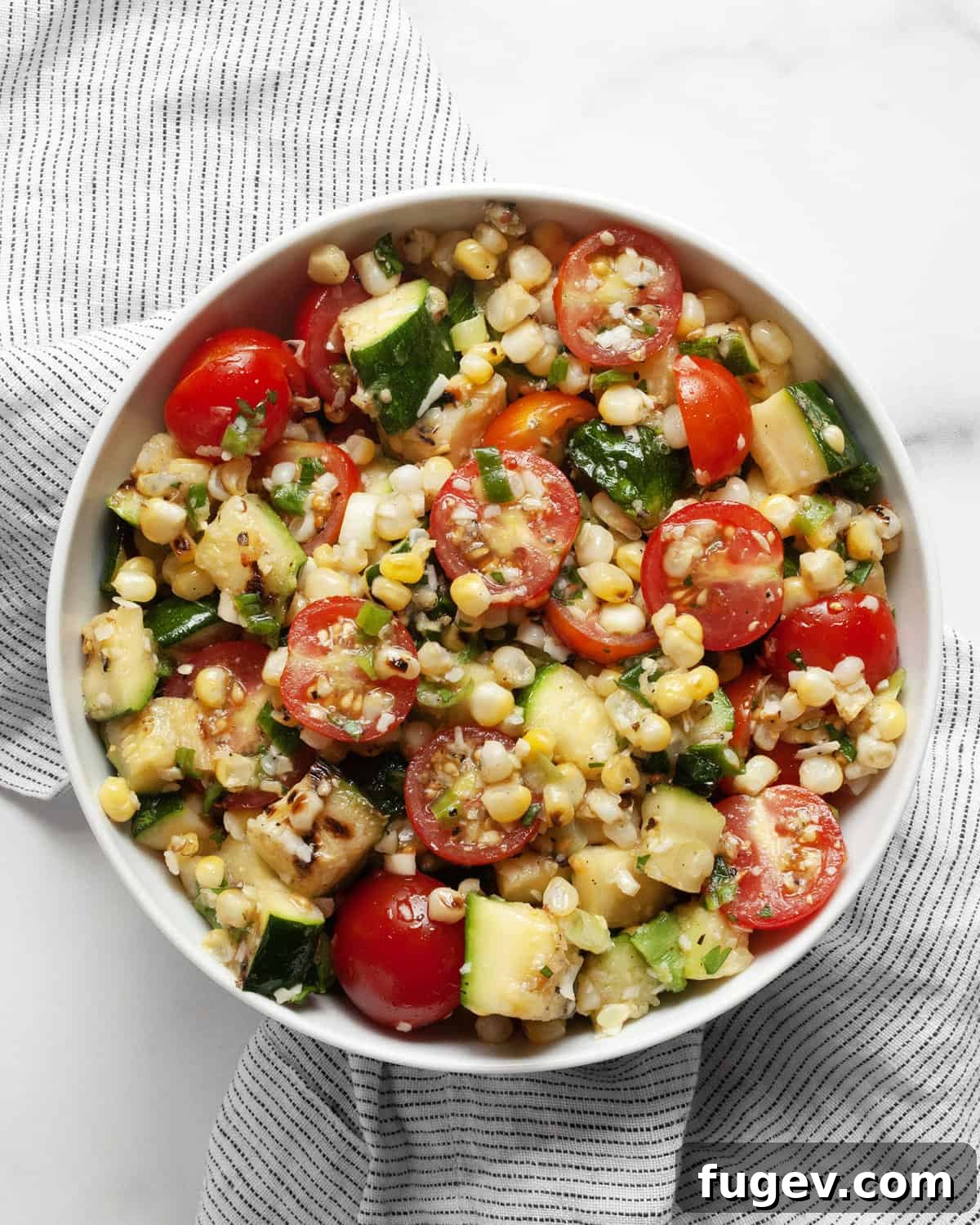 Summer Corn & Zucchini Medley 7 Close-up of grilled zucchini and corn salad with cherry tomatoes in a small white bowl.