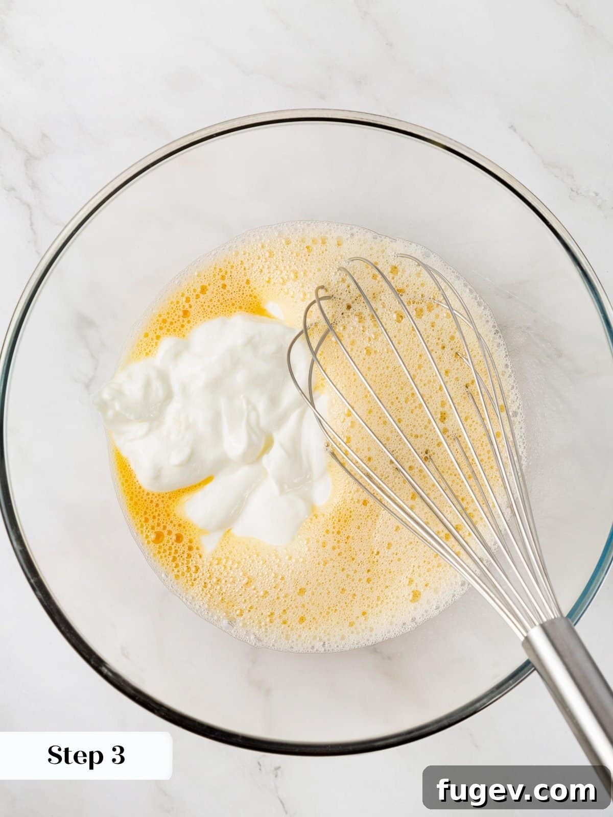 Wholesome Carrot Muffins 6 Wet ingredients for healthy muffins, including egg, maple syrup, Greek yogurt, vanilla, and almond milk, being whisked in a glass bowl.