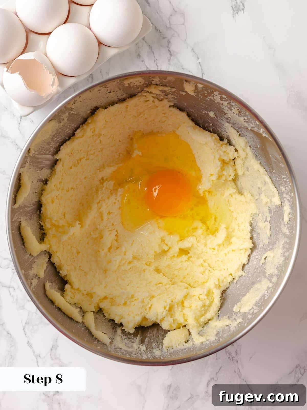 Strawberry Bliss Pound Cake 13 Large eggs being cracked and added one by one to the creamed butter and sugar mixture in a stand mixer, ensuring thorough incorporation.