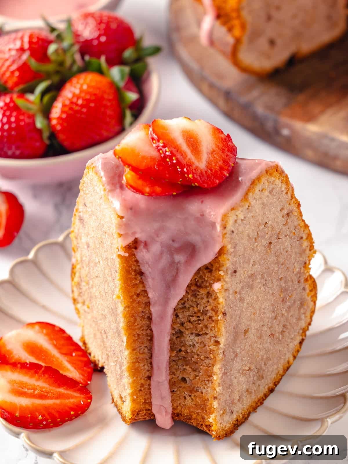 Strawberry Bliss Pound Cake 20 A generous slice of strawberry pound cake, artfully arranged on a pristine white plate with delicate glaze dripping down its sides, ready to be savored.
