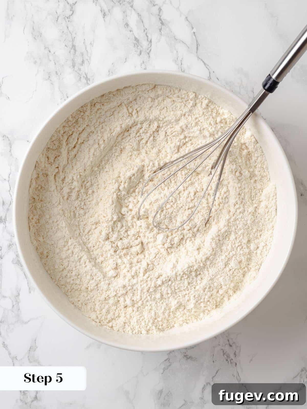 Strawberry Bliss Pound Cake 8 A whisk vigorously blending flour, salt, and baking soda together in a large mixing bowl to ensure even distribution of dry ingredients for the cake.