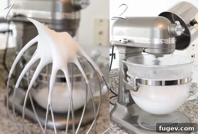 Glossy, stiff egg whites whipped to perfection, shown clinging to a silver whisk attachment.