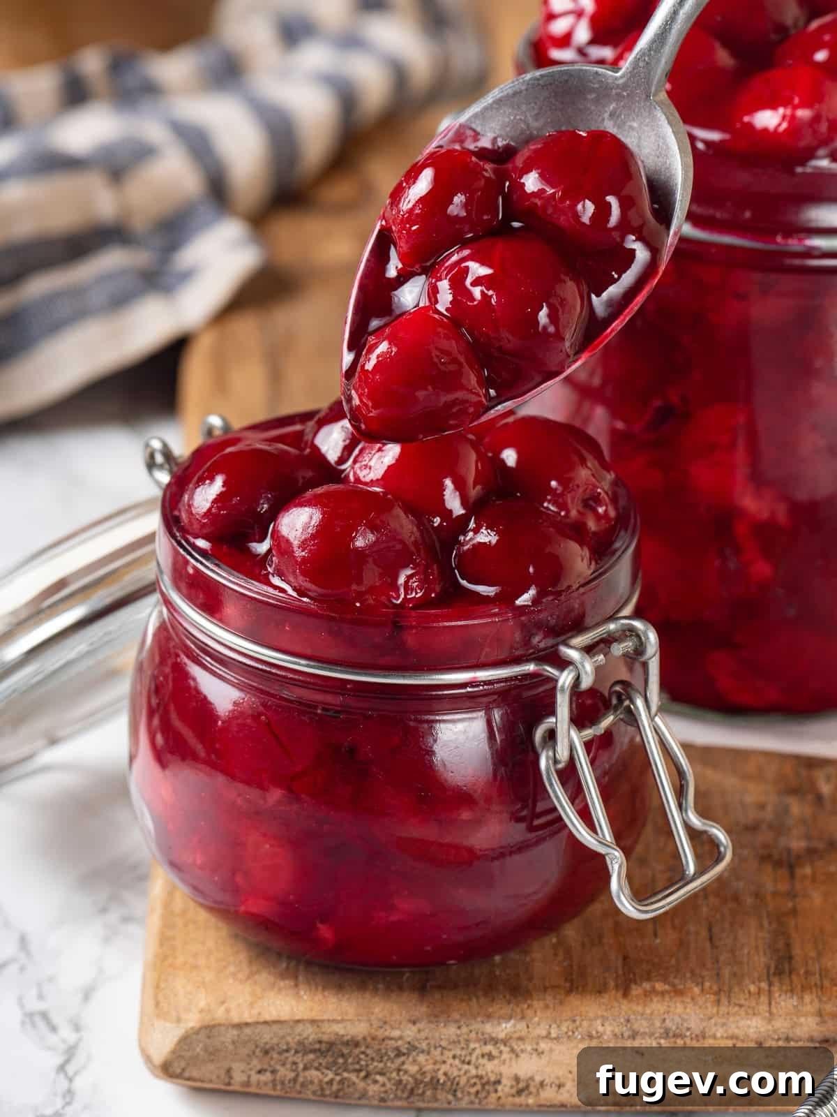Homemade Cherry Pie Filling Perfection 2 Cherry pie filling being spooned from a small jar, showing its texture and shine, ready for delicious desserts.