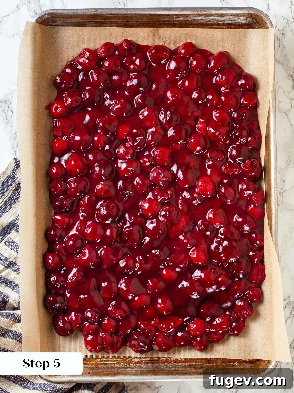Homemade Cherry Pie Filling Perfection 7 Finished cherry pie filling cooling on parchment-lined baking sheet, deep red and glossy throughout, ensuring even cooling.