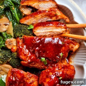 Thick gochujang sauce coating pan-seared chicken pieces with mushrooms in a bowl.