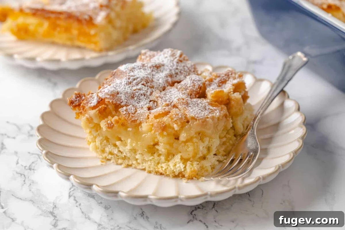 Melted Butter Dream 3 A silver fork poised by a slice of gooey butter cake, revealing distinct layers of golden crust and a rich, gooey vanilla filling.