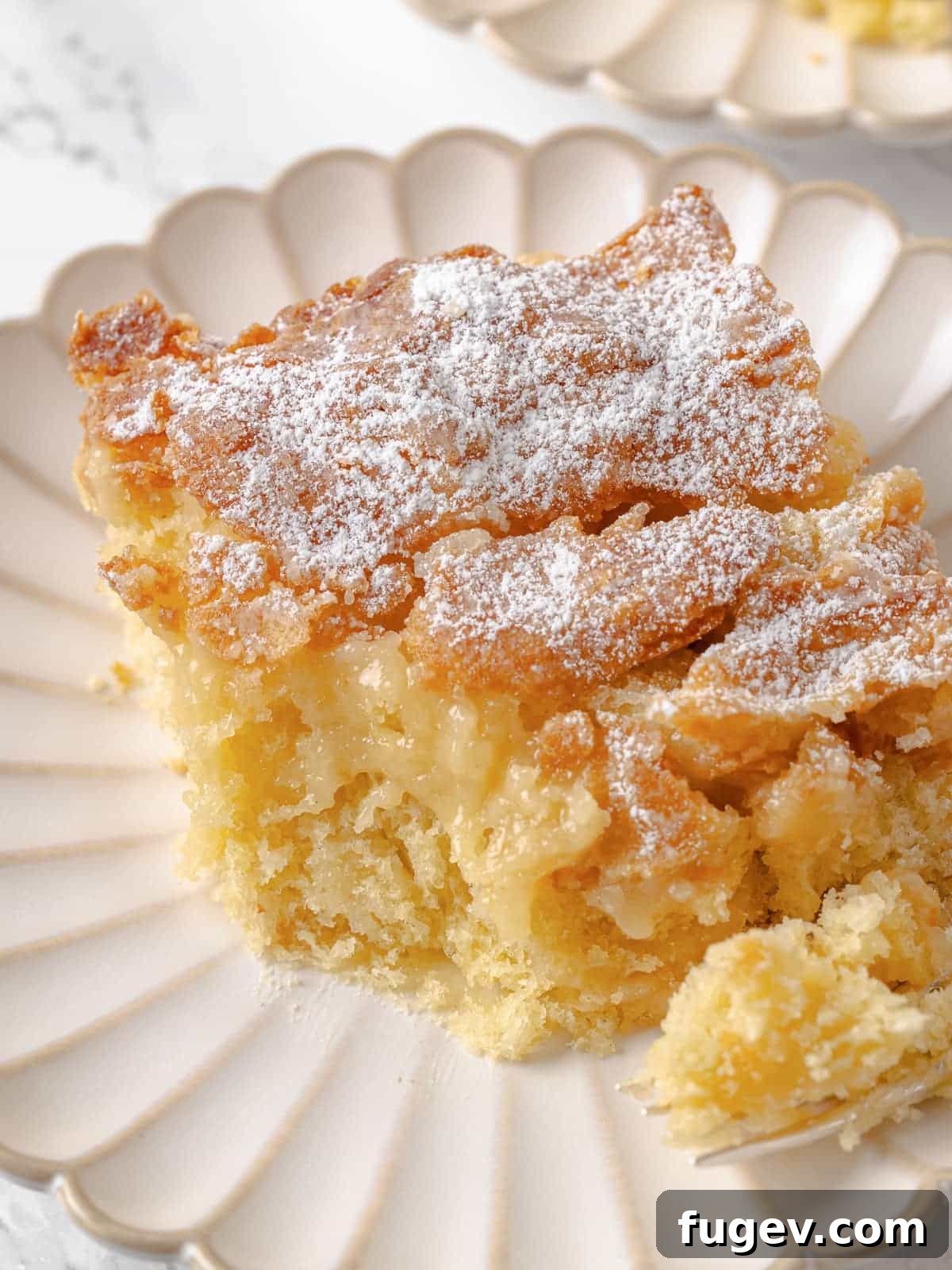 Melted Butter Dream 24 A single slice of gooey butter cake with a bite taken, showcasing its soft, moist texture and incredibly gooey center.