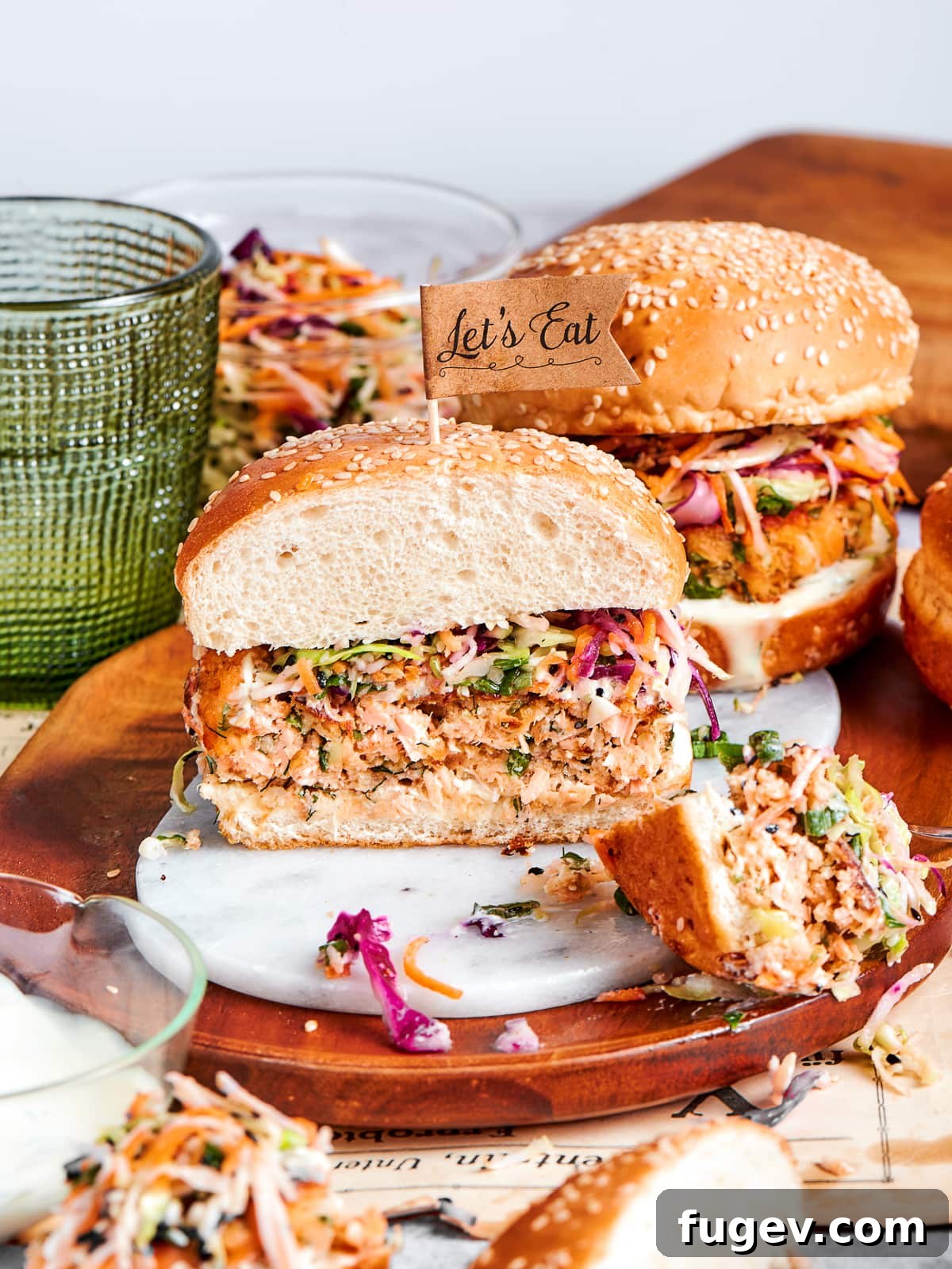 Gourmet Salmon Burgers 2 Hearty salmon burger with crisp slaw and sesame bun on a wooden serving dish.