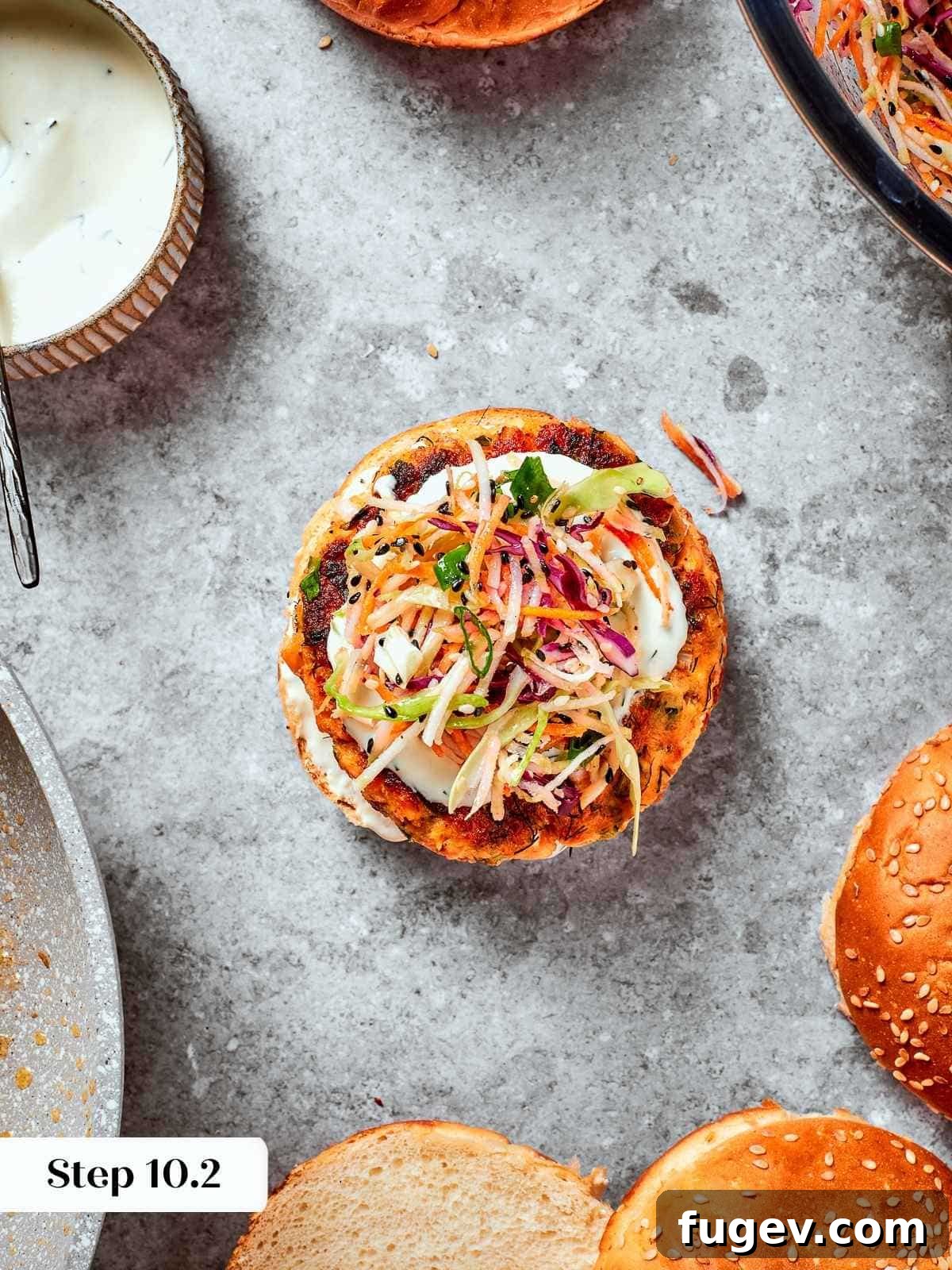 Gourmet Salmon Burgers 12 Assembled burger with top bun off showing layers of salmon, slaw, and sauce.