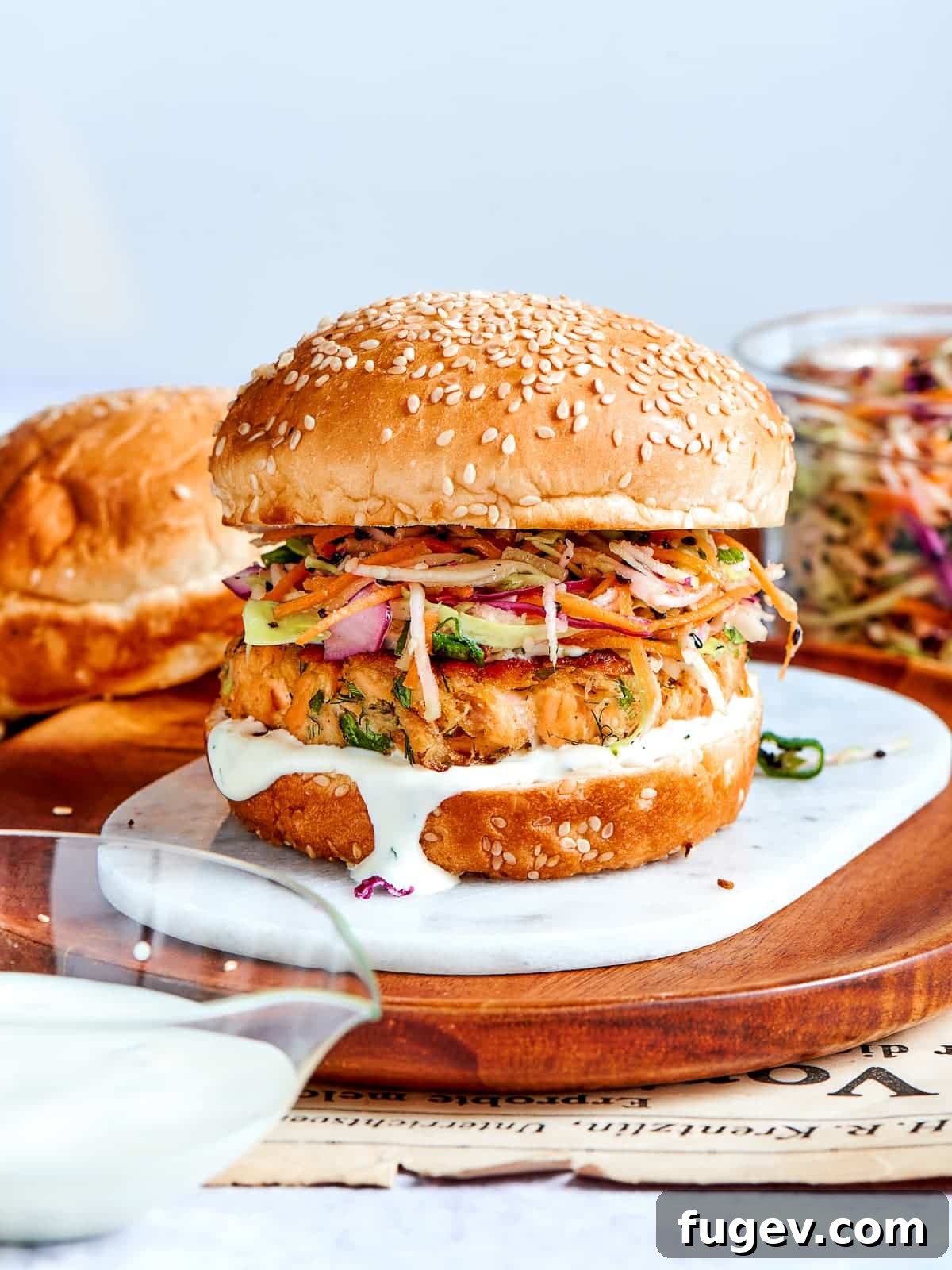 Gourmet Salmon Burgers 14 Salmon burger topped with sesame bun, served on wood with slaw spilling out.