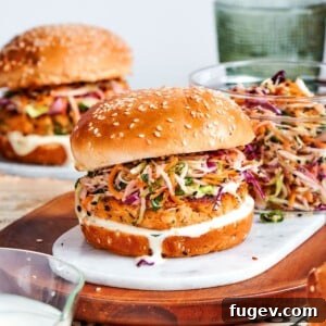 Gourmet Salmon Burgers 15 seasoned salmon patty showing fresh herbs and lemon zest inside assembled burger.