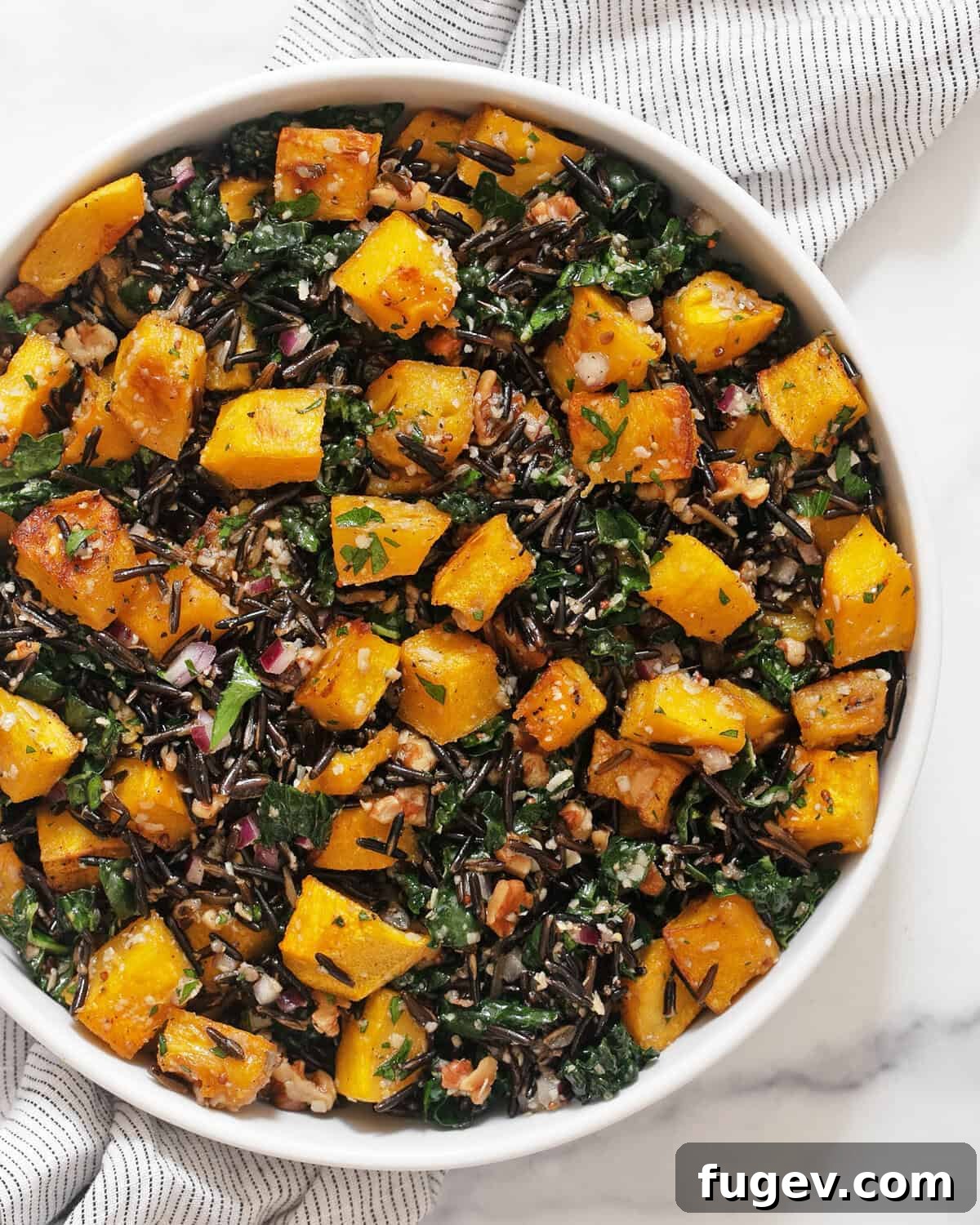 Autumn Harvest Wild Rice and Pumpkin Medley 2 A beautifully presented bowl of roasted pumpkin wild rice salad, garnished with fresh herbs, ready to be served.