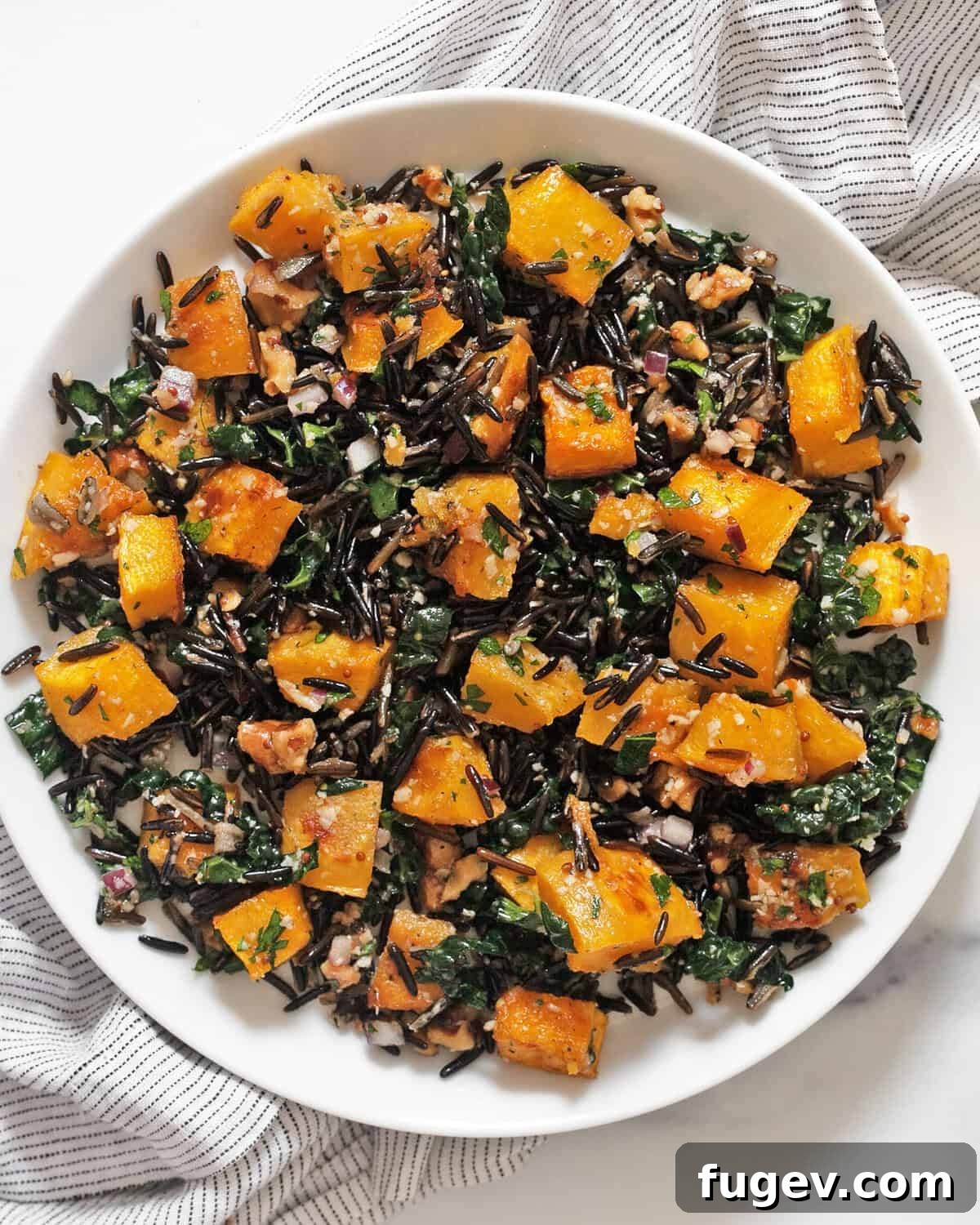 Autumn Harvest Wild Rice and Pumpkin Medley 7 A single serving of roasted pumpkin wild rice salad on a white plate, showcasing its vibrant colors and textures, ready to be enjoyed.
