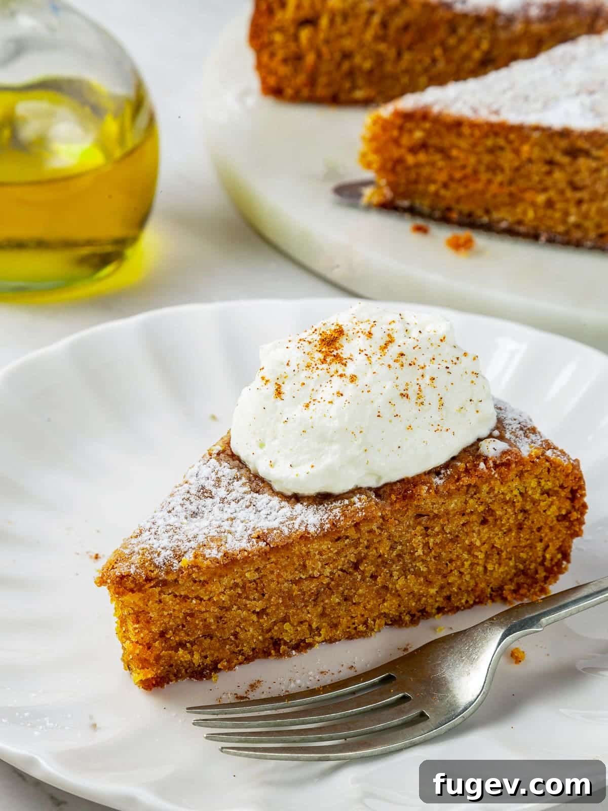 Velvety Pumpkin Olive Oil Cake 13 One generous, perfectly spiced piece of moist pumpkin olive oil cake resting elegantly on a pristine white plate, with a fork nearby, inviting a delightful taste.