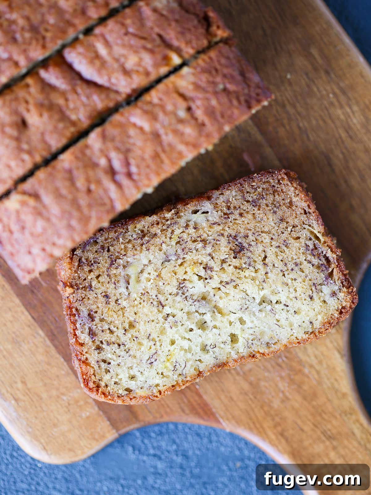 The Ultimate Moist Banana Bread 4 Freshly sliced banana bread resting on a rustic wooden cutting board, ready to be served.